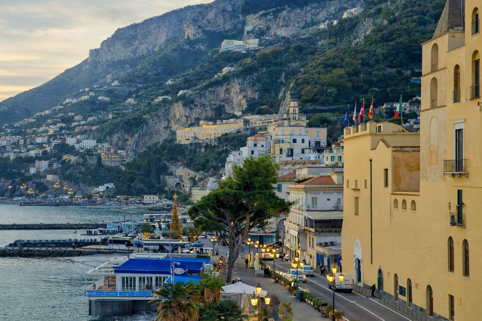 Amalfi al tramonto con la promenade illuminata e l'architettura storica dell'Antica Repubblica Marinara